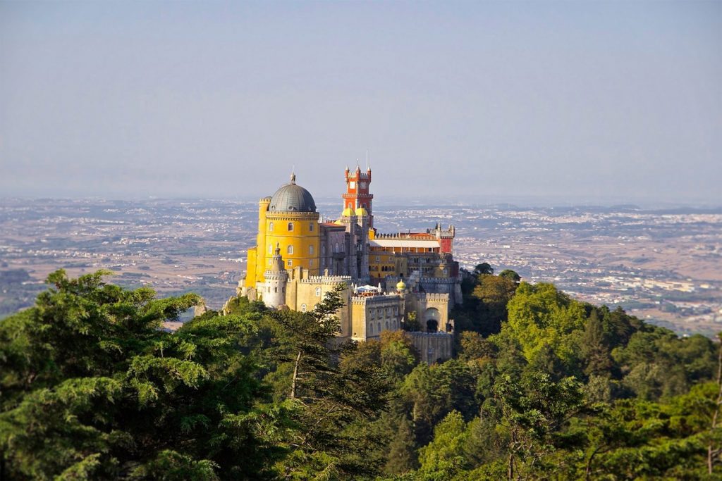 gray and yellow castle at the top of a hill at Pena Palace Sintra